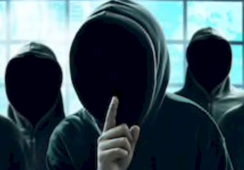 The image shows three figures in hoodies with their faces hidden, one of them holding a finger to their lips as if signaling for silence.