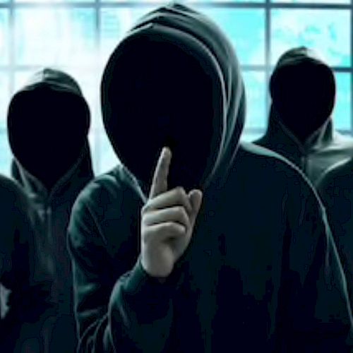 The image shows three figures in hoodies with their faces hidden, one of them holding a finger to their lips as if signaling for silence.