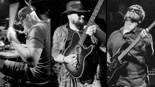 The image shows three musicians performing: a drummer, a guitarist with a hat, and another guitarist wearing sunglasses, captured in black and white.