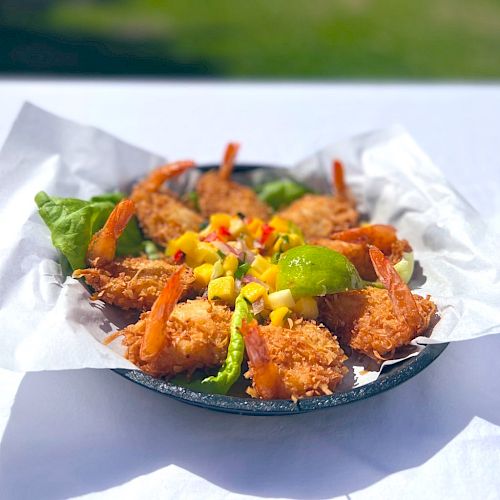 A plate of fried shrimp arranged in a circle on white paper, garnished with lettuce and topped with a colorful salsa, is shown.